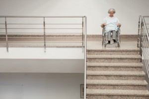 Elderly lady in wheelchair at top of stairs in hospital
